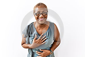 Mature hispanic woman wearing glasses standing over isolated background smiling and laughing hard out loud because funny crazy