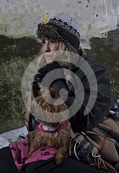 Mature homeless woman leaning against an old wall