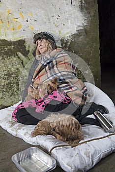 Mature homeless woman leaning against an old wall