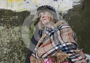 Mature homeless woman leaning against an old wall