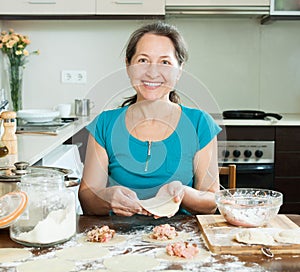 Mature housewife making meat dumplings