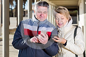 mature husband and wife go nearby with each other and speak by mobile phone