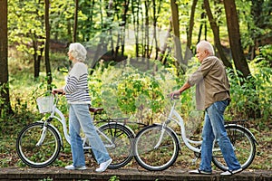Mature husband and wife riding bikes in nature