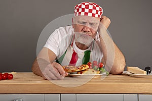 Mature Italian Chef looking at a meal he has prepared