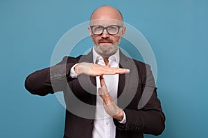 Mature italian man in glasses and suit giving showing time out hands gesture