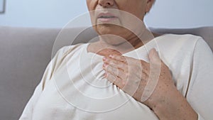 Mature lady hardly breathing, holding hand on chest, risk of heart attack