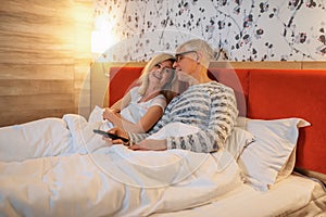 Mature love couple watching TV in bedroom