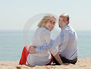 Mature lovers sitting on beach
