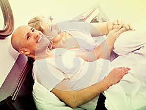 Mature loving couple lounging in bed after awaking cuddling