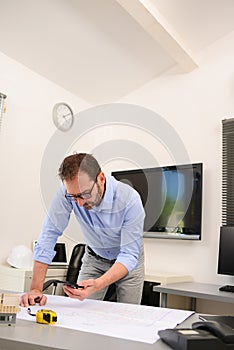 Mature male architect working on laptop on building project drawing sketch in office studio workspace