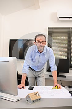 Mature male architect working on laptop on building project drawing sketch in office studio workspace