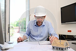 Mature male architect working on laptop on building project drawing sketch in office studio workspace