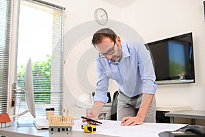 Mature male architect working on laptop on building project drawing sketch in office studio workspace