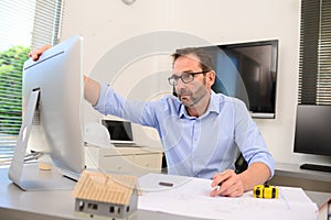 Mature male architect working on laptop on building project drawing sketch in office studio workspace