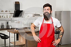 Mature male. Bearded man cook. Bearded man in red apron. Restaurant or cafe cook. Man chef cooking. Hipster in kitchen