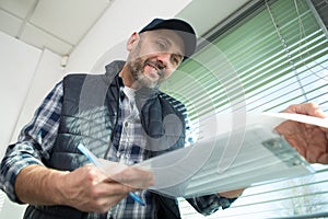 mature male contractor looking at paperwork on clipboard photo