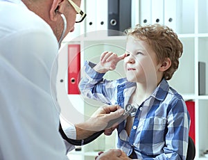 Mature male doctor examining a child patient by stethoscope. Health care concept.