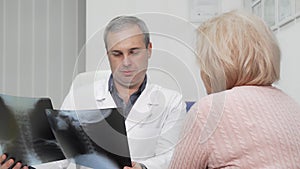 Mature male doctor examining x-ray scans of a senior female patient