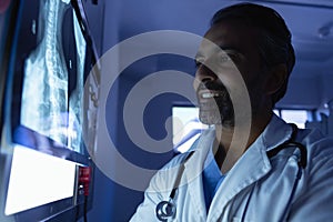 Mature male doctor looking at x-ray on x-ray light box in operation room at hospital