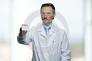 Mature male doctor showing his business card.
