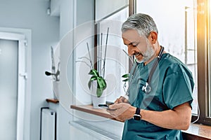 Mature male doctor with smart phone using remote medical consultation applications, texting messages, chatting with distance