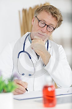 mature male doctor writing on notepad