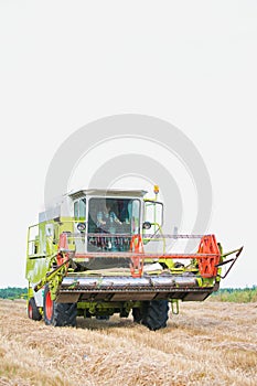 Mature male farmer driving harvester in field