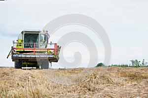 Mature male farmer standing on harvester in field