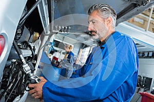 Mature male mechanic working on bus in garage