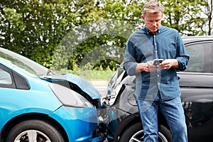 Mature Male Motorist Involved In Car Accident Calling Insurance Company Or Recovery Service