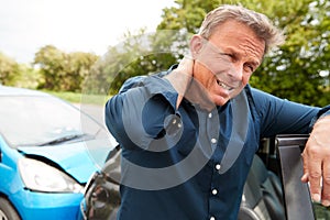 Mature Male Motorist With Whiplash Injury In Car Crash Getting Out Of Vehicle