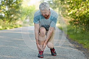 Mature male pulled his leg during outdoor training, suffers from terrible pain, poses outside. Displeased senior man pensioner has