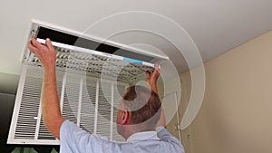 Mature Male Replacing a Furnace Air Filter and Dusting Grille