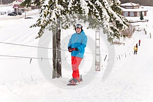 Mature male snowboarder using ski drag rope lift to rise up to the slope top at ski resort