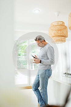 Mature male standing using smartphone