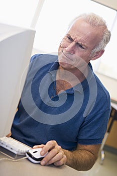Mature male student frowning at computer monitor