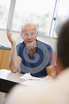 Mature male student gesturing in class