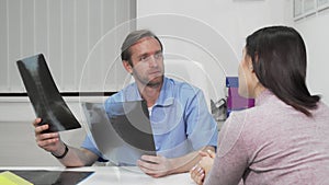 Mature male surgeon examining x-ray scans of a female patient