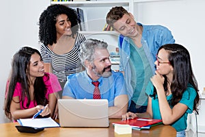 Mature male teacher talking with group of multi ethnic college students