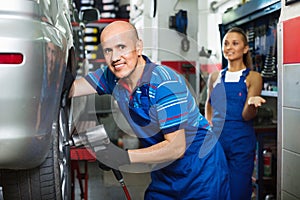 Mature male technician fitting new car tyre