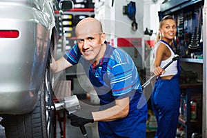 Mature male technician fitting new car tyre