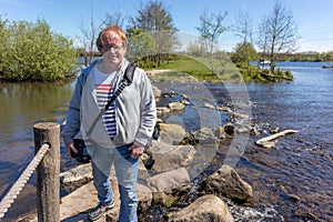 Mature male tourist standing on the steps of Brug Molenplas, with his camera, smiling