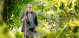 Mature male traveler in green forest. Walk along the green route. Adventure is ageless