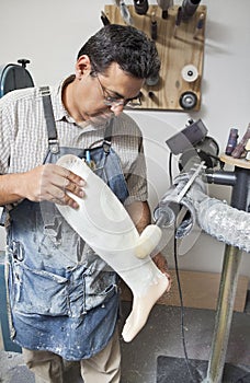 Mature male worker buffing prosthetic limb photo