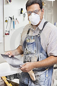 Mature male worker polishing prosthetic limb in workshop