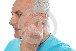 Mature man adjusting hearing aid on white