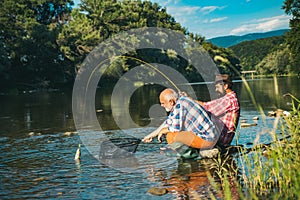 Mature man with adult son fishing. Fisher masculine hobby. Successful fly fishing. Cheerful mature fisherman fishing in