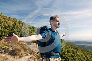 Mature man with backpack hiking in mountains in summer.