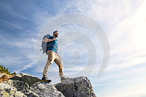 Mature man with backpack hiking in mountains in summer.