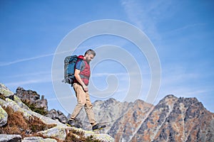 Mature man with backpack hiking in mountains in summer.